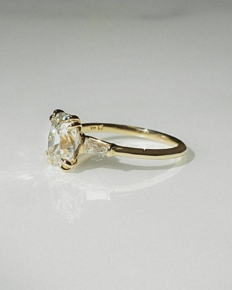 1.60 carat cushion cut lab grown diamond three stone ring in a double claw mount with sculpted dome shank. A classic forever engagement or promise ring, ideal as an anniversary or birthday gift for her—crafted with sustainable brilliance and refined style.