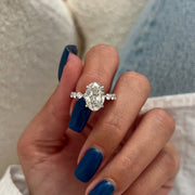 May include: A silver oval engagement ring with a large oval-shaped diamond center stone and smaller round diamonds set in a pave setting on the band.