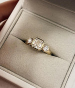 Load image into Gallery viewer, Asscher Cut Trilogy Diamond Engagement Ring featuring a 1.5ct IGI Certified Asscher Cut Lab Grown Diamond with round lab grown diamond side stones in solid gold. Three-stone engagement ring with 1.82ct total carat weight.