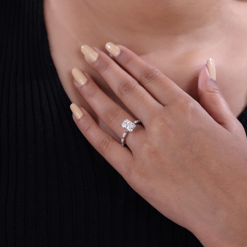 Lab grown radiant cut diamond engagement ring set in claw prong with marquise side stone created in 14k gold.