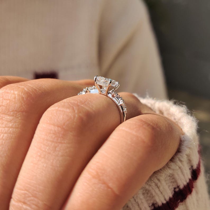 Radiant cut diamond ring featuring round diamond cluster setting.