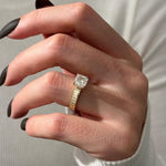 Load image into Gallery viewer, May include: A gold ring with a large, square-cut diamond. The band has a ribbed design. The ring is held up by a hand with black nail polish.